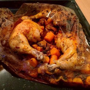 Dieses Bild zeigt die Hähnchenschenkel mit Gemüse in einem Bratschlauch auf dem Backblech