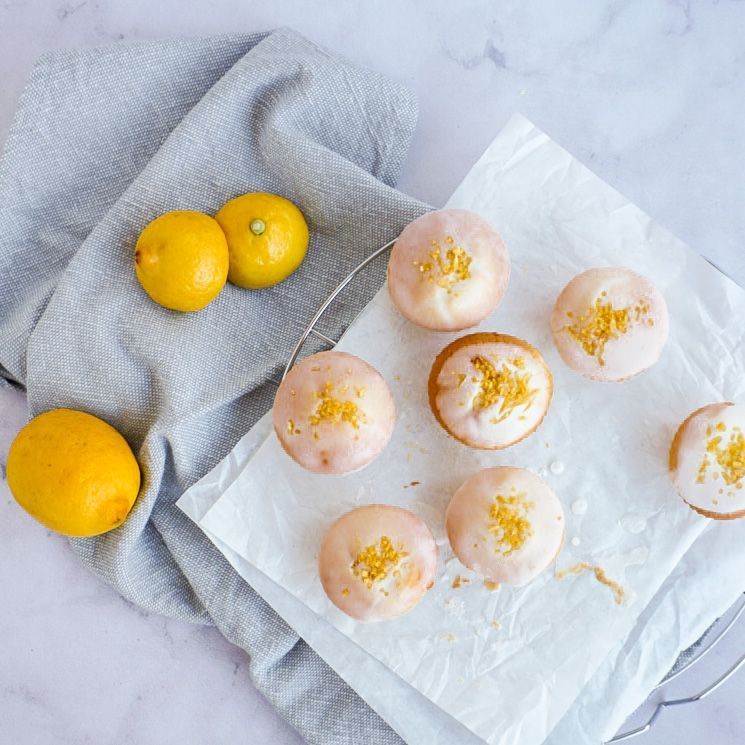 Dieses Bild zeigt sieben Zitronenmuffins und drei Zitronen von oben