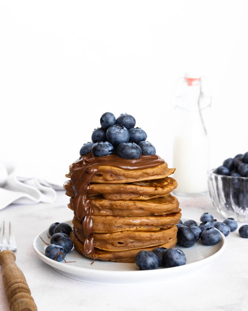 Ein Stapel vegane Schoko Pancakes mit Schokosauce und Blaubeeren